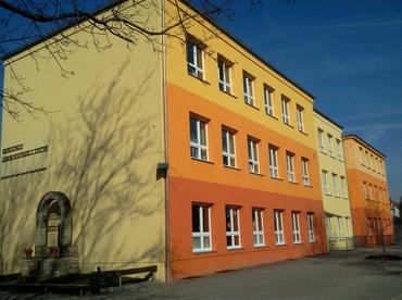 Vorderansicht der Schule mit Brunnen