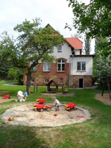 Blick über den Spielplatz auf das Gebäude
